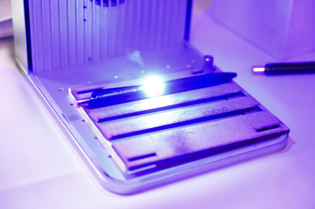 Laserové gravírovanie pera pod modrým svetlom.